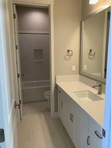 a bathroom with a granite countertop sink a toilet and shower