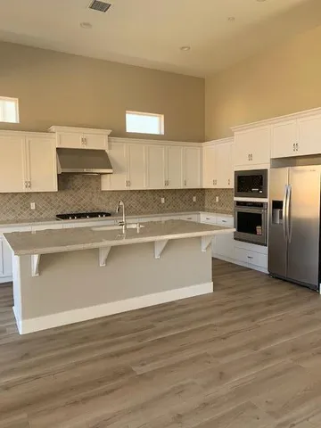 a white kitchen with granite countertop a stove top oven and cabinets