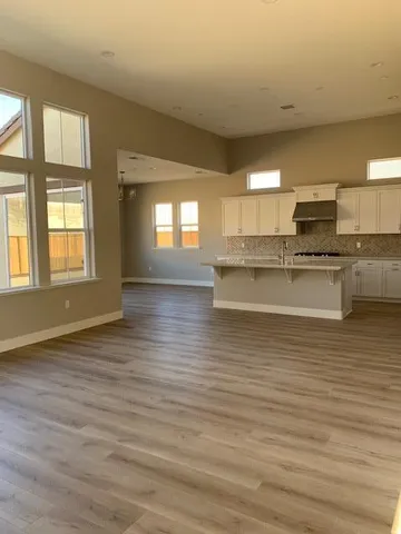 a view of a kitchen with kitchen island a sink wooden floor and a large window