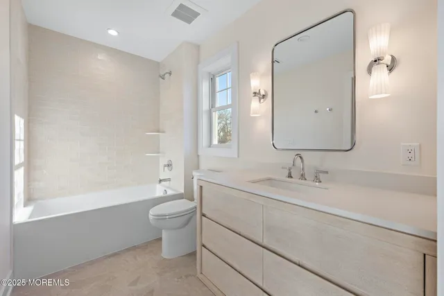 a bathroom with a granite countertop sink a toilet and a mirror