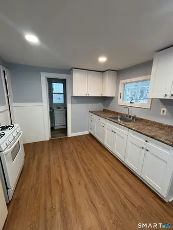 a kitchen with granite countertop white cabinets and wooden floor