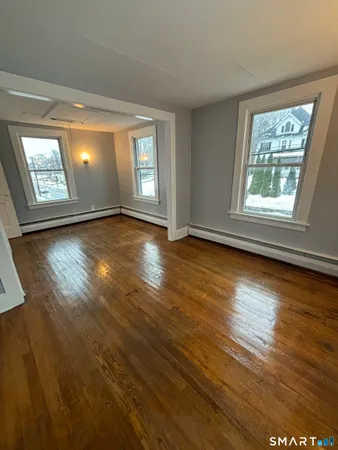 a view of an empty room with wooden floor and a window