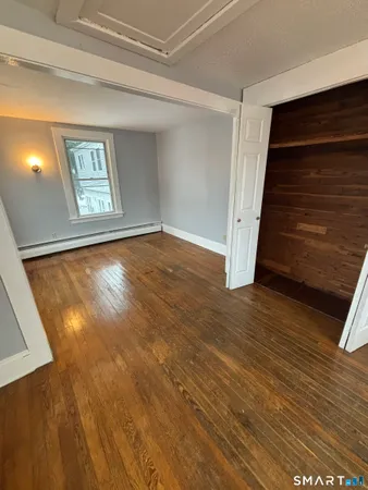 a view of an empty room with wooden floor and stairs
