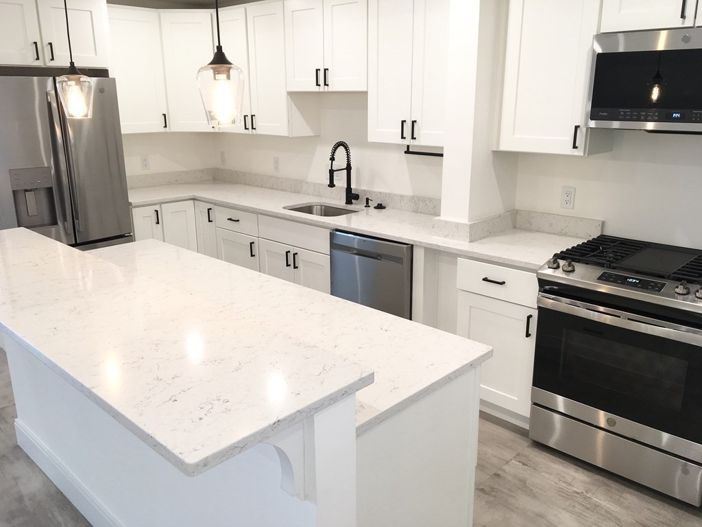 2239 Washington Street, Unit 200 Canton, MA 02021 - Photo 5 of 35 a kitchen with stainless steel appliances a sink a stove a refrigerator and cabinets