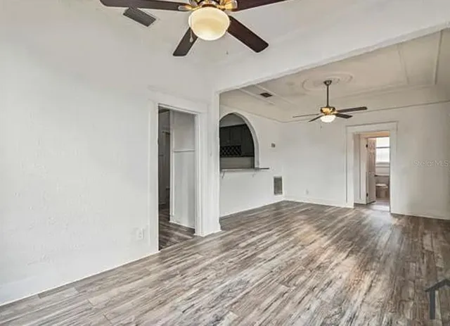 a view of empty room with wooden floor and ceiling fan
