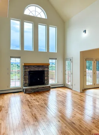 an empty room with wooden floor fireplace and windows