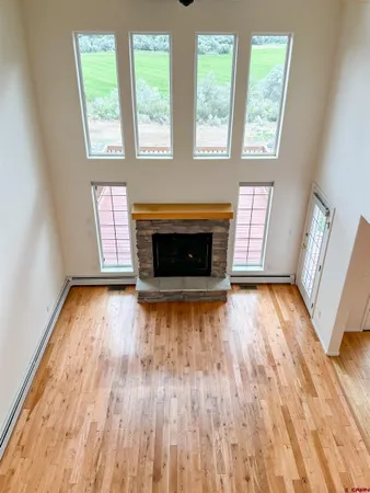 an empty room with wooden floor fireplace and windows