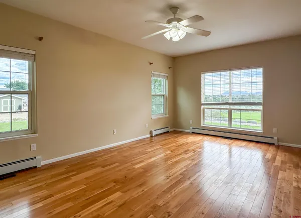 a view of an empty room with a window and wooden floor