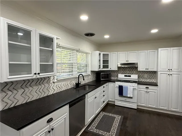 a kitchen with stainless steel appliances granite countertop a sink a stove and cabinets