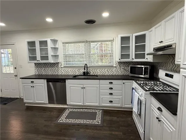 a kitchen with granite countertop stainless steel appliances a stove sink and cabinets