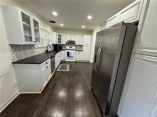 a kitchen with stainless steel appliances granite countertop a refrigerator a sink and wooden floors