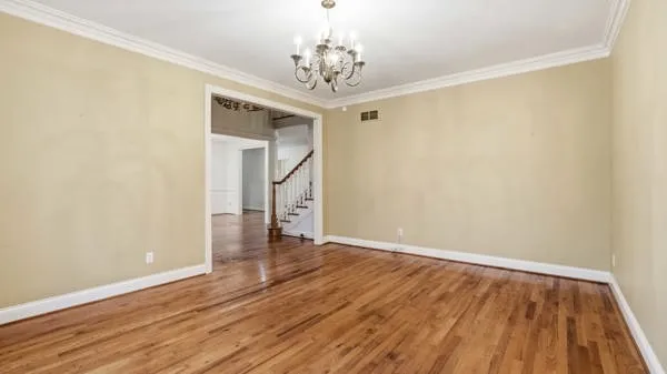 a view of a hallway with wooden floor and a chandelier