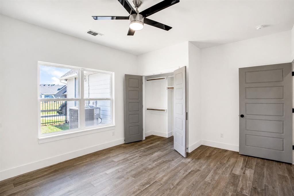311 Dobbs Trail Springtown, TX 76082 - Photo 22 of 33 an empty room with wooden floor cabinet and windows
