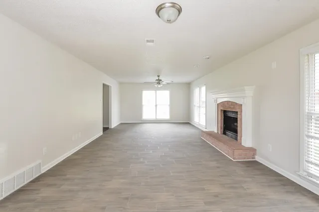 an empty room with windows and fireplace