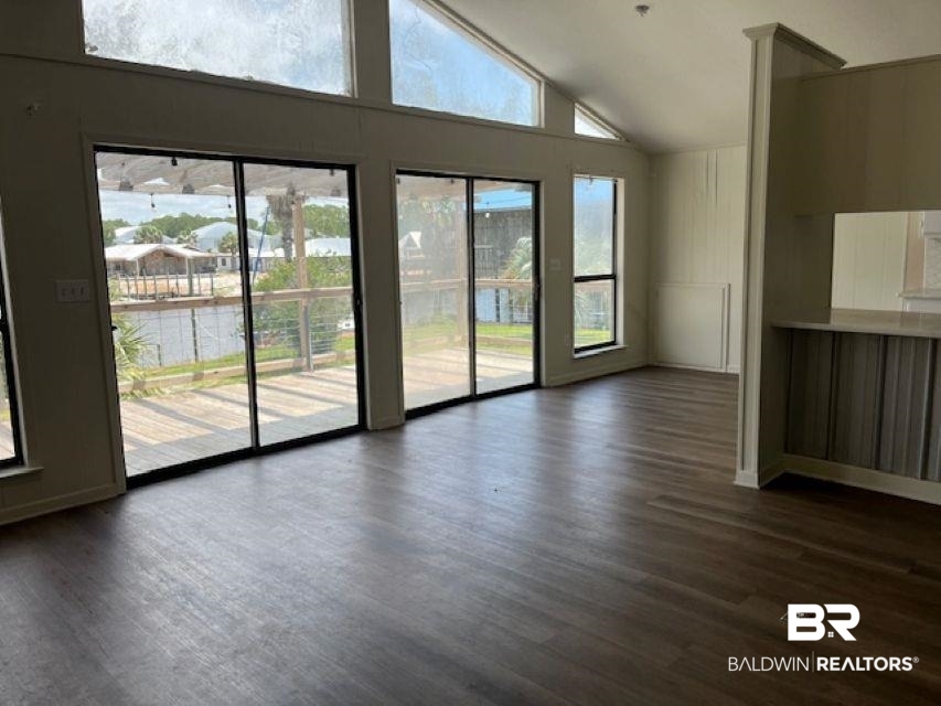 26225 Marina Road Orange Beach, AL 36561 - Photo 4 of 8 Unfurnished living room featuring dark wood-style flooring, high vaulted ceiling, and baseboards