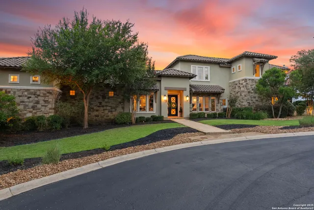 a view of a white house next to a yard with big trees