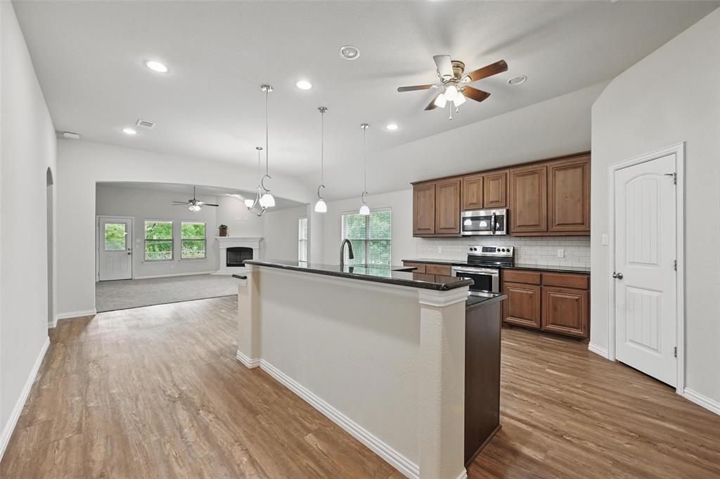 512 Hidden Spgs Trail Azle, TX 76020 - Photo 2 of 27 a kitchen with stainless steel appliances a stove top oven a sink dishwasher a refrigerator and a dining table with wooden floor