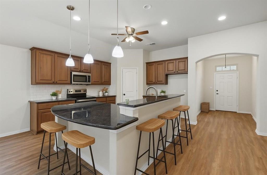 512 Hidden Spgs Trail Azle, TX 76020 - Photo 7 of 27 a kitchen with stainless steel appliances granite countertop a stove top oven a sink a refrigerator with a dining table and chairs with wooden floor