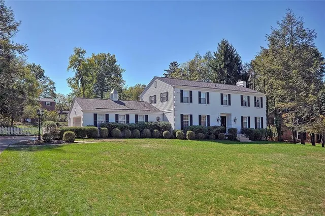 a view of a house with a big yard and large trees