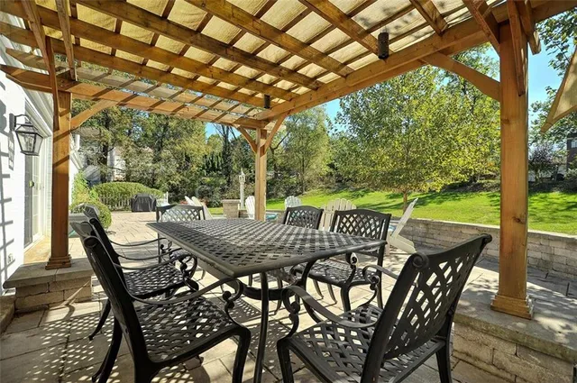a view of a patio with table and chairs under an umbrella with a large tree
