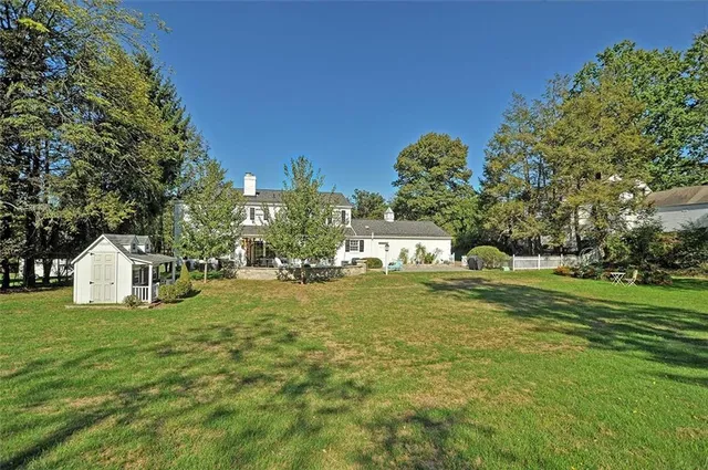 a view of a house with a big yard potted plants and large tree