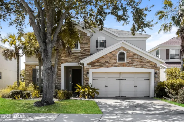 a view of a white house with a large windows and a tree