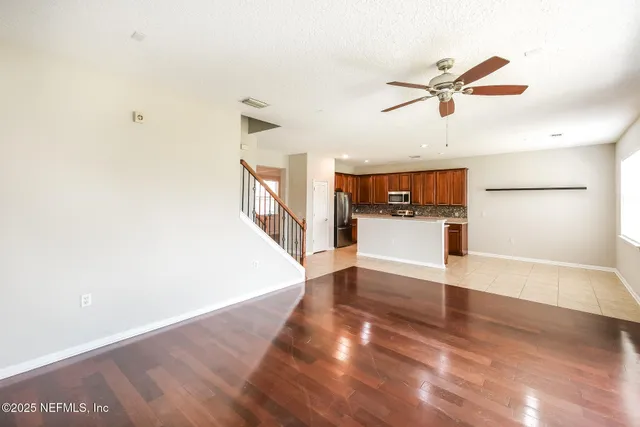 a view of a living room with a ceiling fan and wooden floor