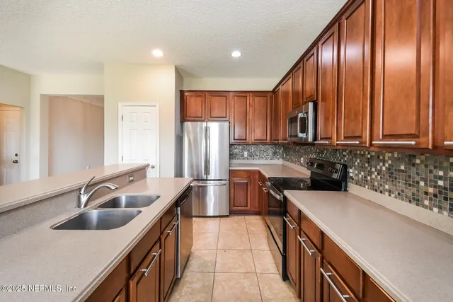 a kitchen with stainless steel appliances granite countertop a sink a stove and a refrigerator