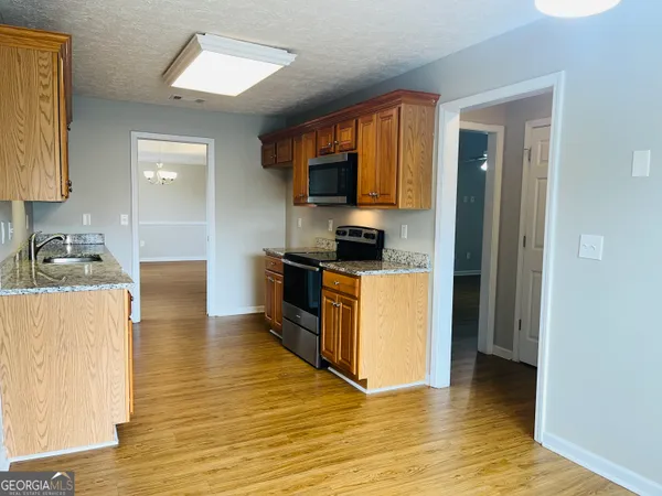 a kitchen with granite countertop a stove top oven a sink and a refrigerator