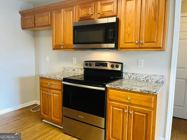 a kitchen with stainless steel appliances granite countertop wooden cabinets and a stove top oven