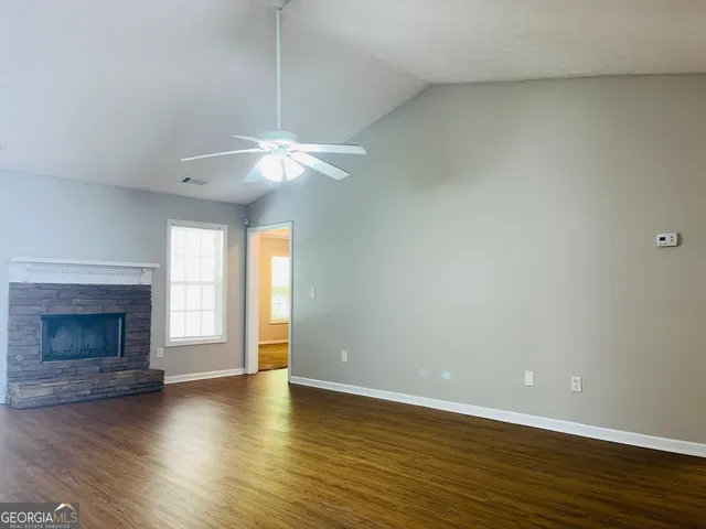 an empty room with wooden floor fireplace and window