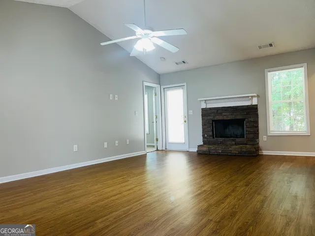an empty room with wooden floor fireplace and windows