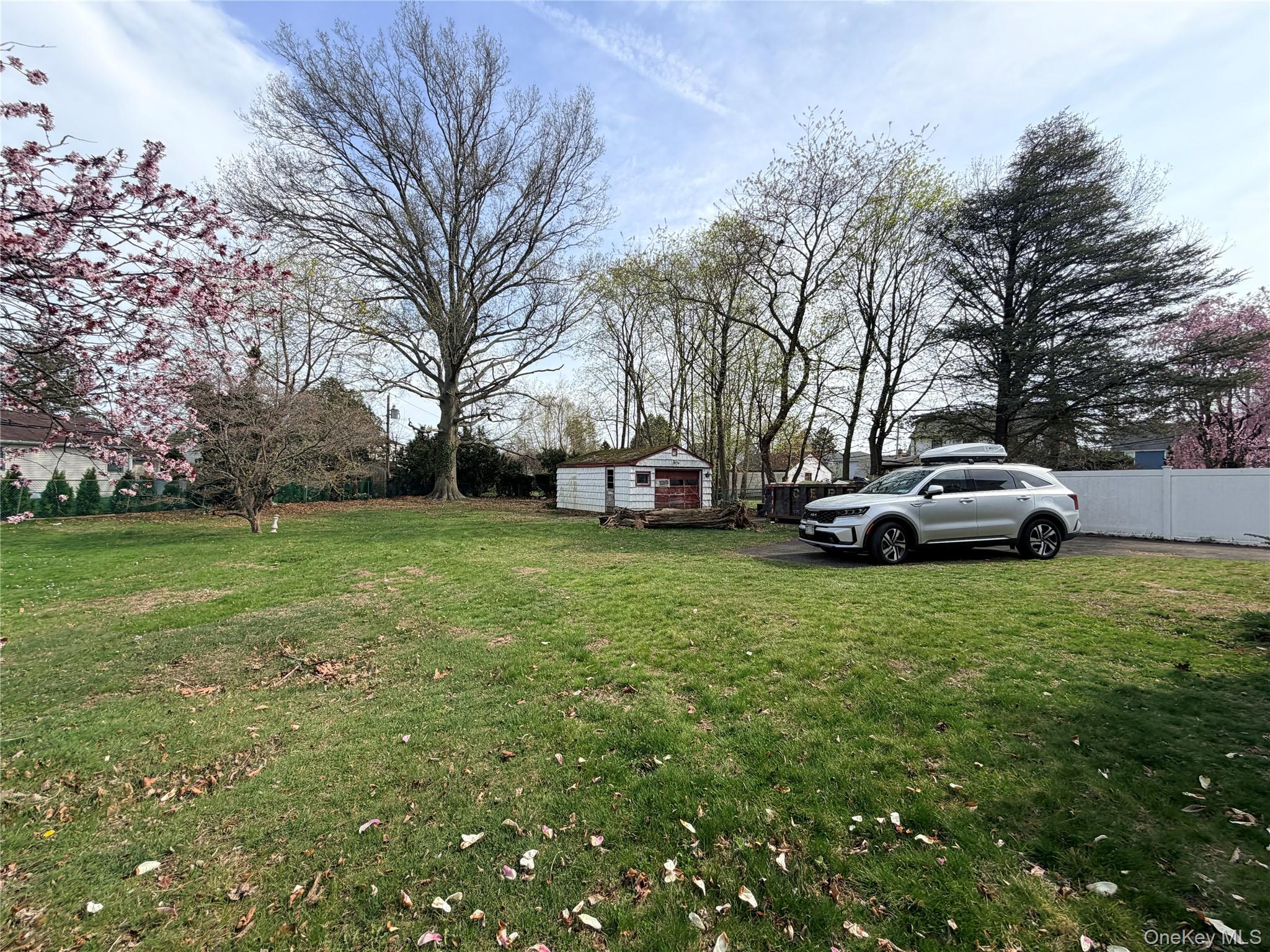 245 Woodbury Road Hicksville, NY 11801 - Photo 34 of 37 a car parked in the grass next to a yard
