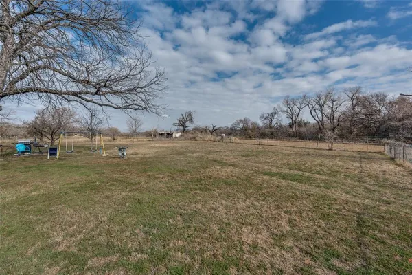 a view of dirt field with large trees