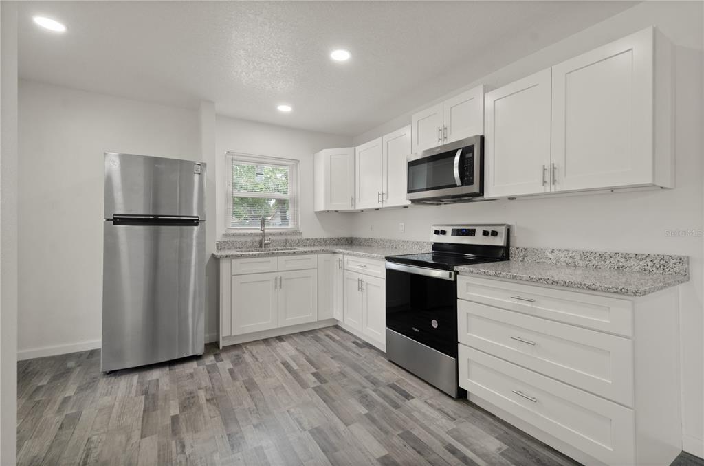 4385 Cassius Street Orlando, FL 32811 - Photo 11 of 21 a kitchen with granite countertop white cabinets and stainless steel appliances
