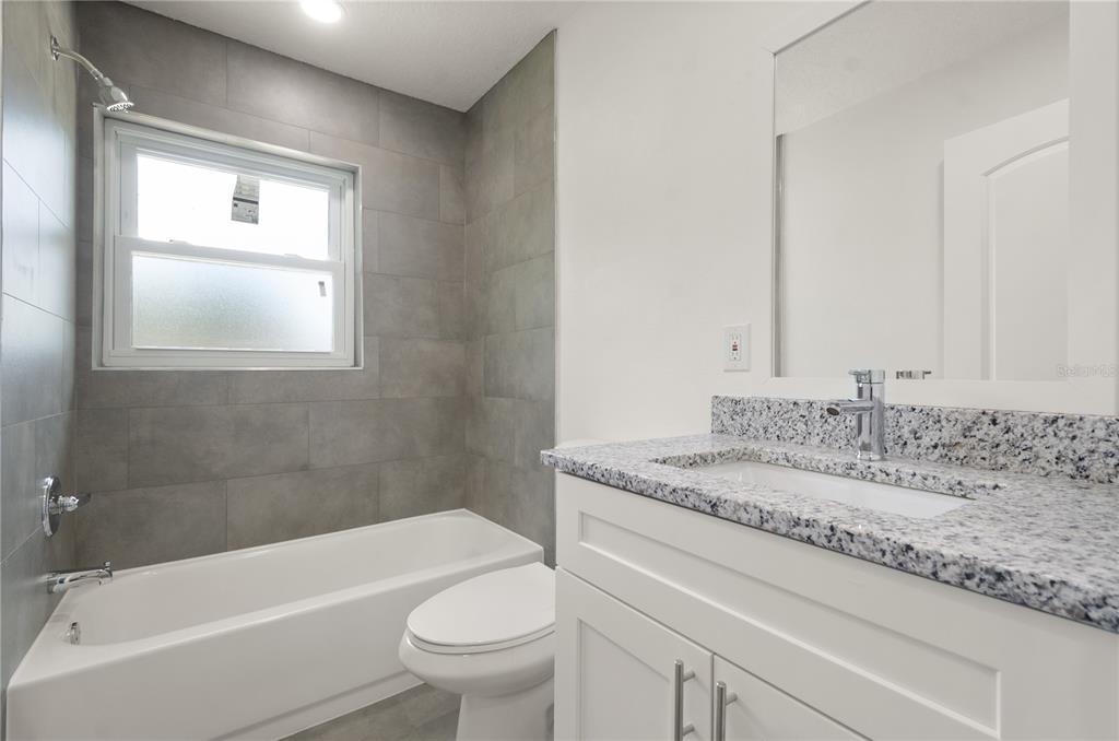 4385 Cassius Street Orlando, FL 32811 - Photo 19 of 21 a bathroom with a granite countertop sink a toilet and bathtub