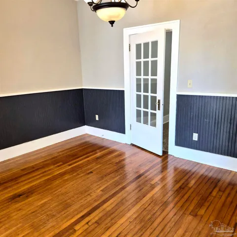 a view of an empty room with wooden floor and windows