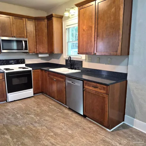 a kitchen with stainless steel appliances granite countertop a stove a sink and a microwave