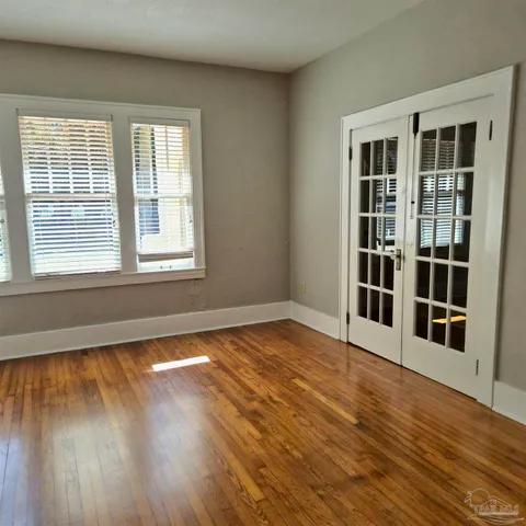 a view of empty room with wooden floor and fan