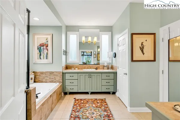 a bathroom with a granite countertop sink a mirror a vanity and a bathtub