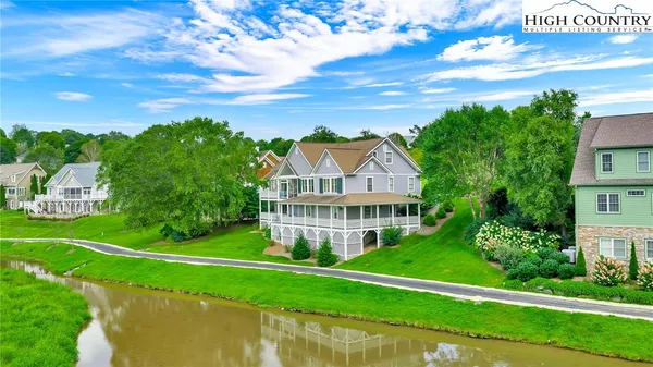a view of a house with a big yard plants and large trees