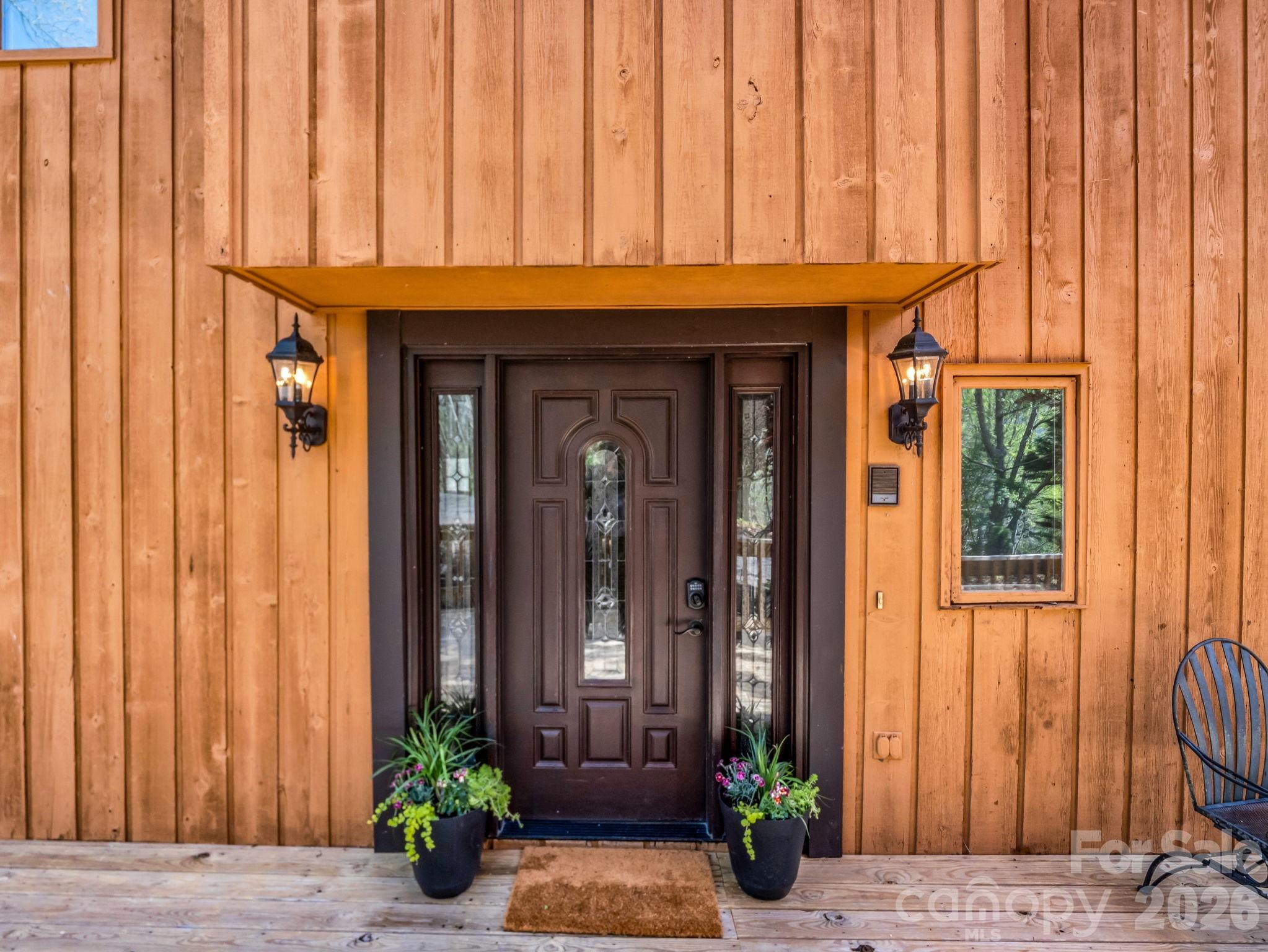 307 Watership Road Lake Lure, NC 28746 - Photo 3 of 48 a front view of a house with potted plants and wooden fence