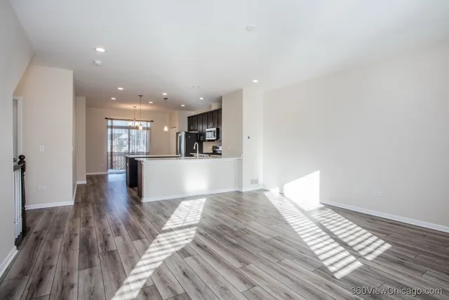 a view of a big room with wooden floor and windows