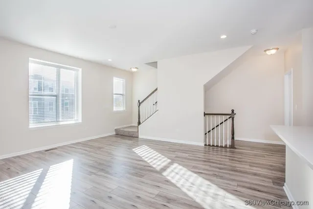 a kitchen with stainless steel appliances a stove a sink a refrigerator white cabinets and wooden floor