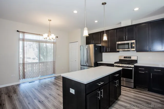 a kitchen with kitchen island granite countertop stainless steel appliances and wooden floor