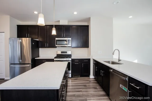a kitchen with kitchen island wooden floor appliances and refrigerator