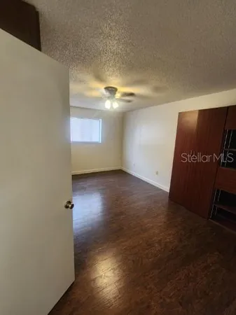 an empty room with wooden floor and windows with curtains