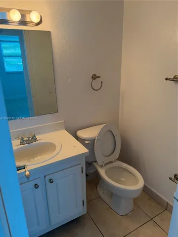 a bathroom with a granite countertop toilet a sink and a mirror
