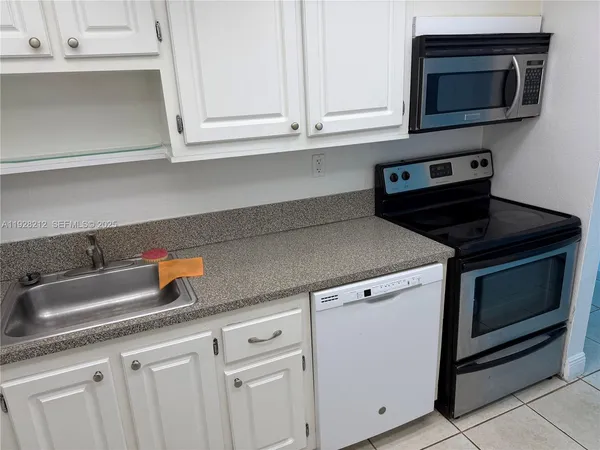 a kitchen with granite countertop white cabinets and a stove top oven