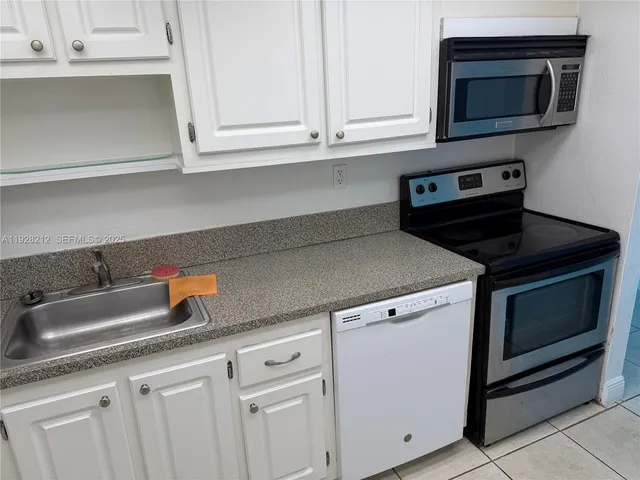 a kitchen with granite countertop white cabinets and a stove top oven